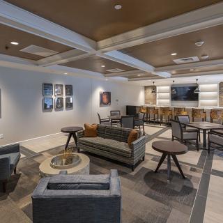 A modern living room with stylish furniture, featuring a sofa, armchairs, and tables, complemented by artwork on the walls.