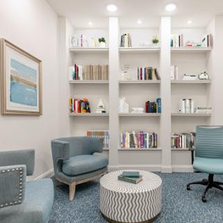 A cozy reading nook featuring modern furniture and a neatly arranged bookshelf.