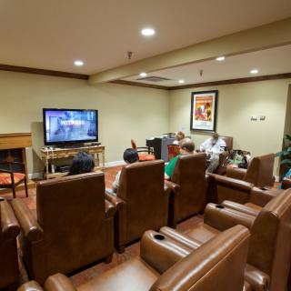 A cozy home theater with leather seating where people are watching television.