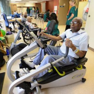 Seniors exercising on stationary bikes in a healthcare facility.