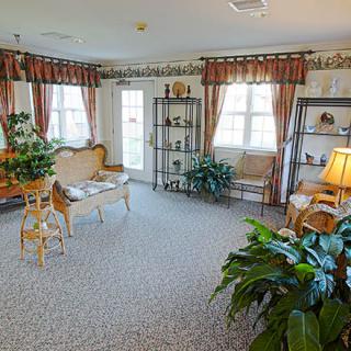 A cozy living room with elegant furniture, large windows, and decorative plants.