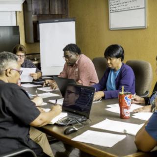 A group of people collaborating around a conference table in an office setting.