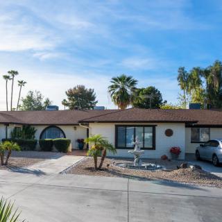 A suburban house with a driveway and palm trees in the background on a sunny day.