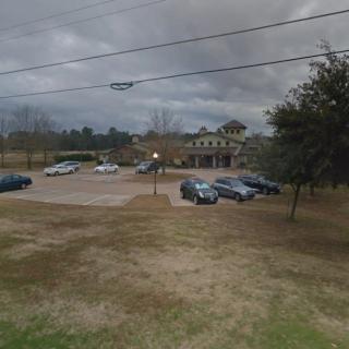 A parking lot with several cars in front of a building under a cloudy sky.