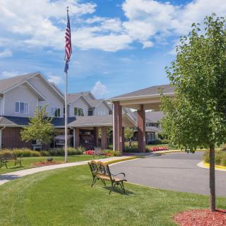 A view of a building with an American flag, surrounded by well-maintained landscaping and benches.