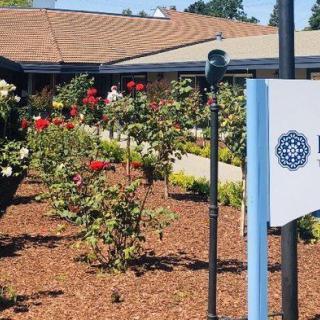 A landscaped garden with vibrant flowers in front of a building and a sign.