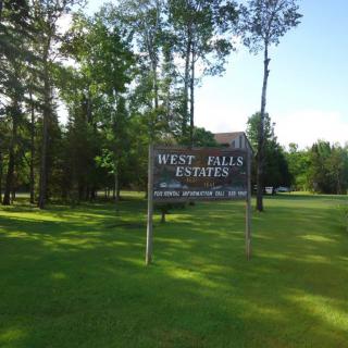 A sign for West Valley Estates surrounded by trees and grass.