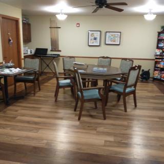 A cozy dining area with a round table, chairs, and wooden flooring.