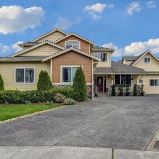 A modern suburban house with a spacious driveway and neatly trimmed landscaping under a partly cloudy sky.