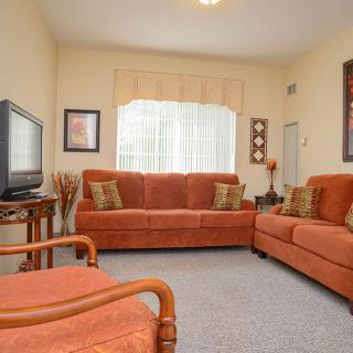 A cozy living room featuring orange sofas and a TV.