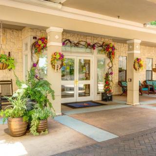A decorated building entrance with potted plants and seasonal decorations.