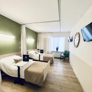 A modern hotel room featuring twin beds, minimalist decor, and ample natural light.