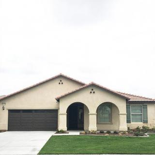 A suburban single-story house with a garage and a well-maintained lawn.