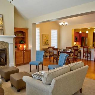 A cozy living room with an open dining area, featuring a fireplace and comfortable seating.