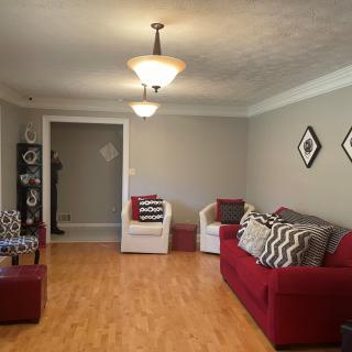A modern living room with a red sofa, wooden flooring, and stylish lighting fixtures.