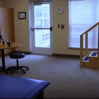 A physical therapy room equipped with a therapy table, exercise area, and basic rehabilitation equipment.