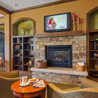 A cozy living room with a stone fireplace, television above, and comfortable seating area.