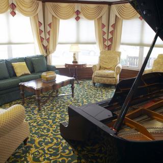 An elegant living room featuring a grand piano, plush seating, and luxurious decor.