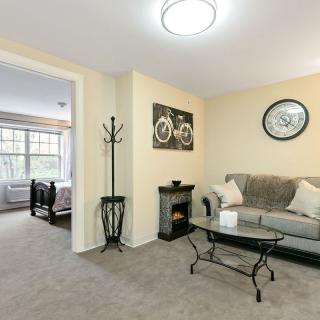 A cozy living room with a sofa, glass coffee table, and wall decor including a clock and artwork.