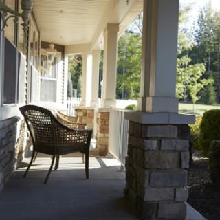 A cozy wicker chair on a porch, inviting relaxation in the warm sunlight.