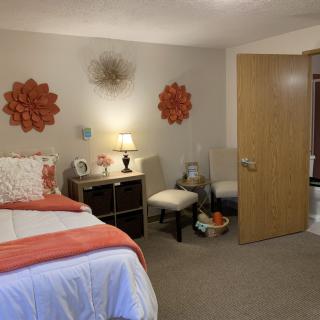 A cozy bedroom with wall decorations, a bed, and a small seating area.