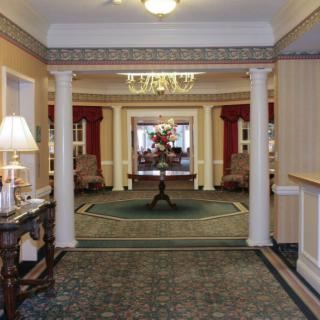 A hotel lobby featuring elegant columns, a chandelier, and decorative furniture.