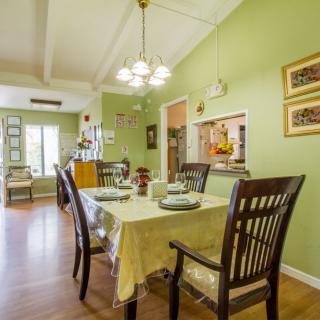 A cozy dining room with green walls, a chandelier, and a well-set table.