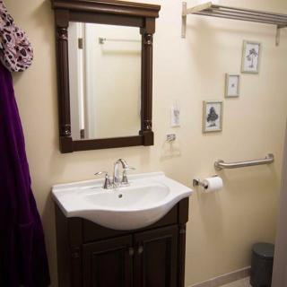 A well-organized bathroom with a mirror, sink, towel rack, and decorative wall art.