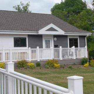 A suburban house with a white fence and landscaped front yard.