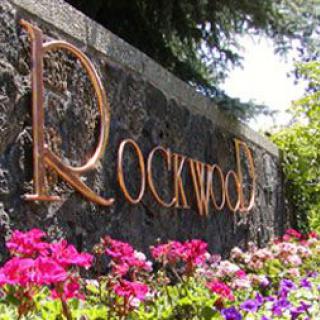 A sign reading 'Rockwood' surrounded by vibrant flowers.