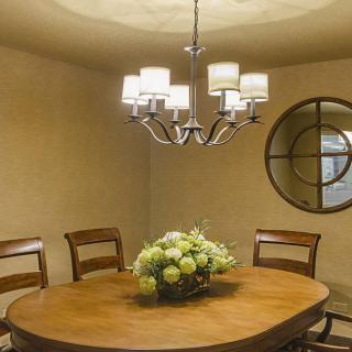 A cozy dining room with a wooden table, surrounded by chairs, featuring a chandelier and decorative mirror.