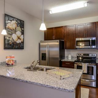 A modern kitchen with granite countertops, stainless steel appliances, and dark wood cabinets.