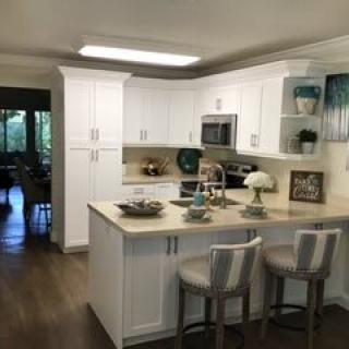 A modern kitchen with white cabinets and a central island featuring bar stools.