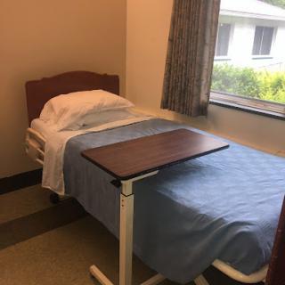 A clean and simple hospital patient room featuring a bed and bedside table.