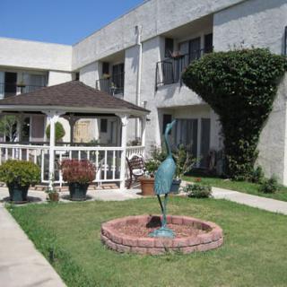 A well-maintained garden area with a gazebo and fountain in front of an apartment building.
