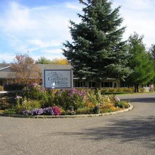 A scenic view of a building surrounded by gardens and trees, with a sign at the entrance.