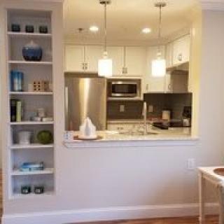 A modern open-concept kitchen with white cabinets and stainless steel appliances.