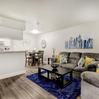 A modern living room with an open kitchen, featuring comfortable seating and stylish decor.