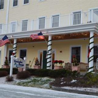 A building with flags and winter decorations on the porch, surrounded by light snow.