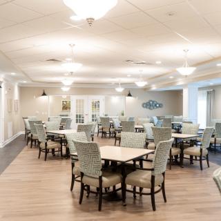 A spacious and well-lit dining area with multiple tables and chairs arranged neatly.