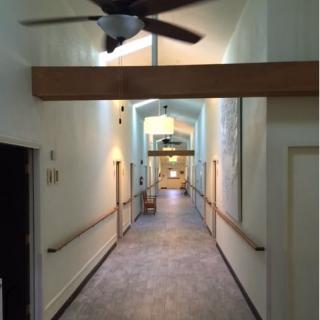 A well-lit corridor with wooden beams and ceiling fans.