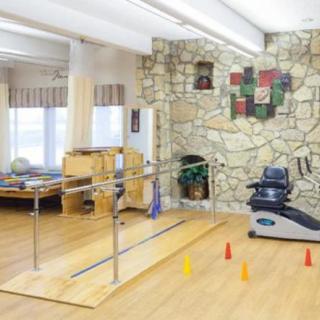 A rehabilitation center room equipped with parallel bars and a stationary bike for physical therapy exercises.