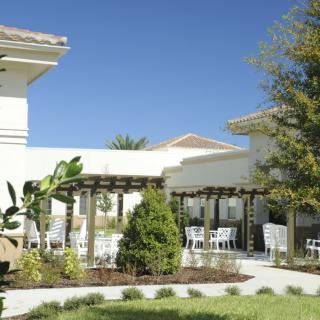 A beautifully landscaped outdoor area with a pergola and seating, adjacent to a building.