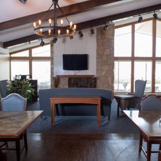 A cozy lounge area with a chandelier, fireplace, and large windows.