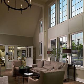A spacious living room with high ceilings and large windows, furnished with a cozy sofa and elegant lighting.