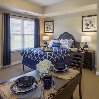 A cozy bedroom with an adjacent dining area, featuring a stylish bed, elegant decor, and ample natural light.