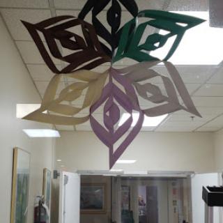 Colorful paper snowflakes suspended in an interior space.