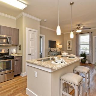 A modern kitchen features stainless steel appliances and an island counter with bar stools, creating an open and inviting space.