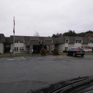 A view of a building with a parking lot under a cloudy sky.