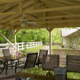 A cozy patio with outdoor seating under a pergola, overlooking a lush garden.